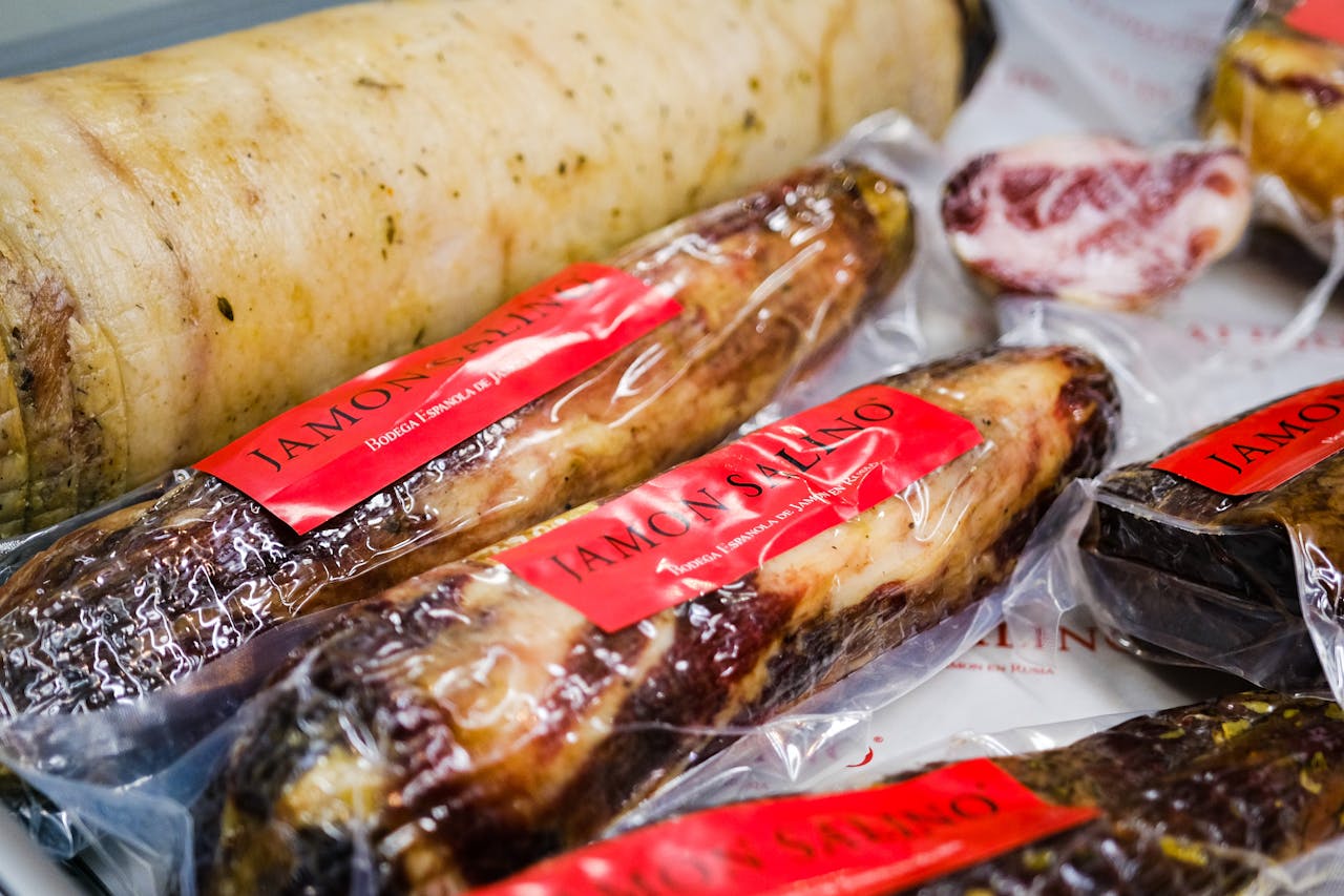 Home Close-up view of Spanish cured meats like jamón and sausages in plastic packaging, ready for sale.